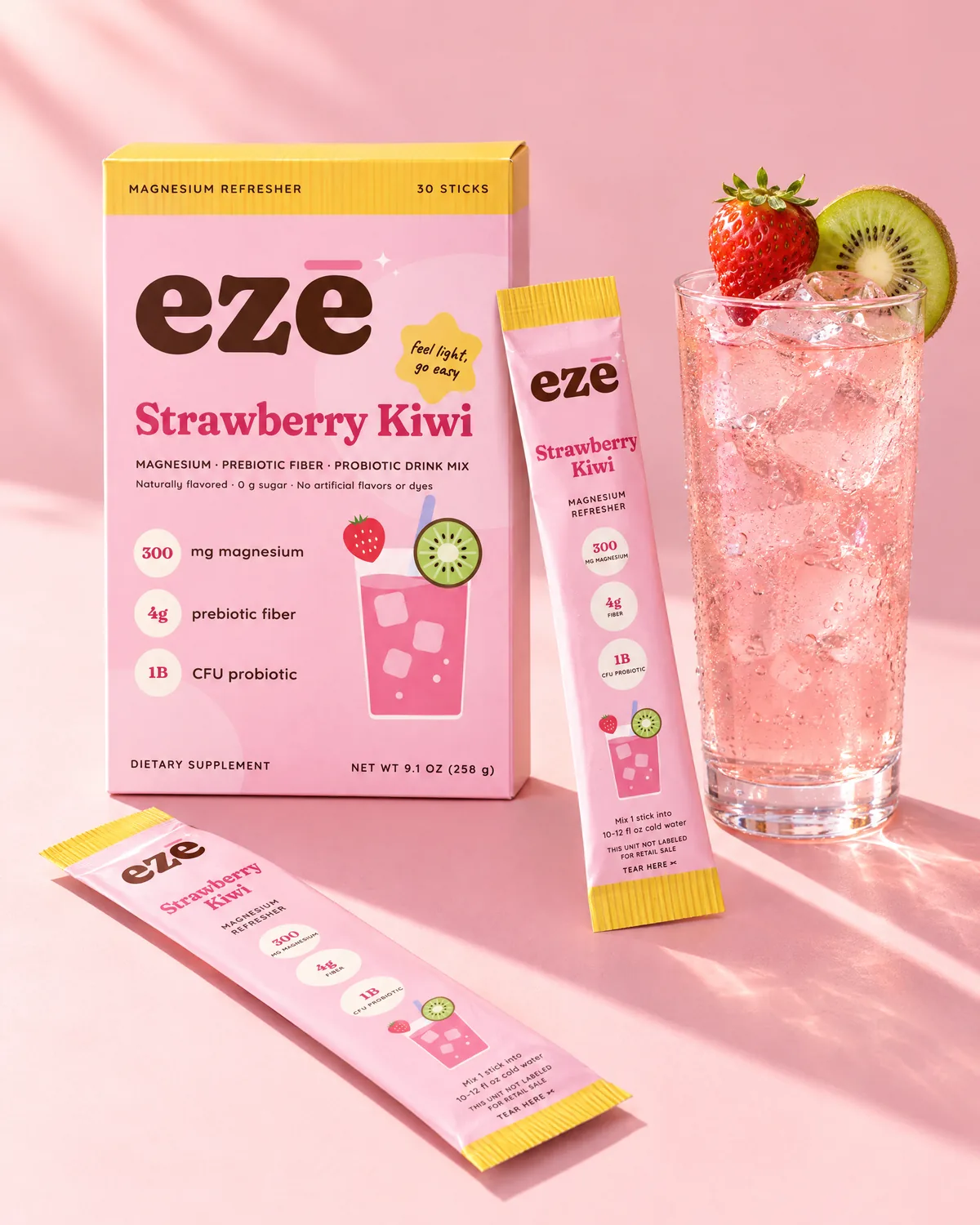 ezē Strawberry Kiwi box with two stick packs next to an iced pink drink